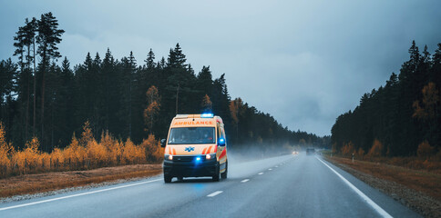 Fototapeta na wymiar Defocused photo of ambulance car on the highway, blurred image of an emergency car running on the forest road at the cloudy evening