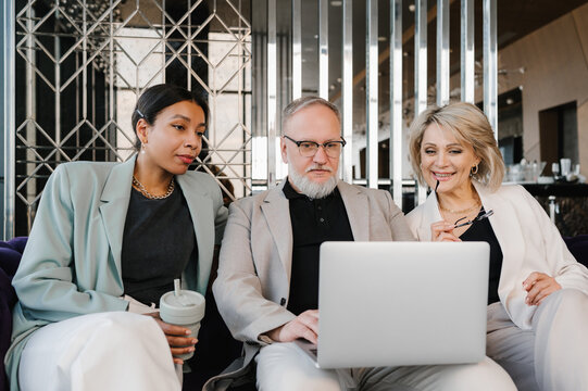 Diverse concentrated colleagues working on laptop