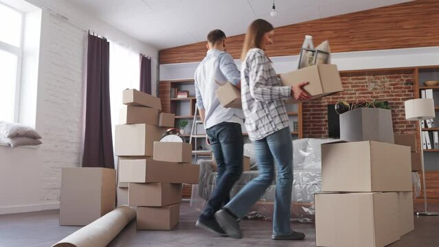 Young couple carrying boxes in new apartment on moving day.New accommodation or rented flat.Happy homeowners portrait on relocation day. Real estate and tenancy concept. Loan mortgage for young family