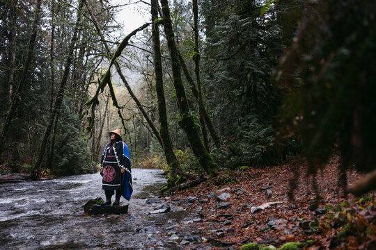 Woman standing near river in ceremony dress.