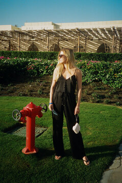 Girl posing at camera while stand near red fire hydrant
