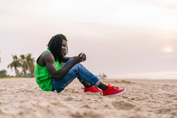 Black man browsing smartphone on seaside