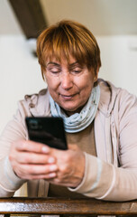 Grandmother looking mobile phone in living room