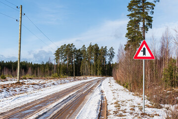 Melting ice on a country road in winter day. Road junction with priority over minor road from the...