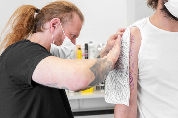 Obraz premium Skilled Tattoo artist putting a sketch on the arm of a man. High quality photo