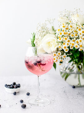 Pink Gin and Tonic Cocktail Garnished with Blueberries and Rosemary 