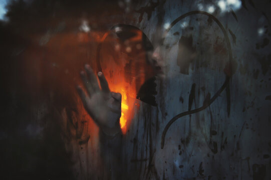 A girl draws a heart on a steamy wintery window