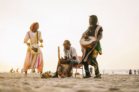 African men playing instruments near sea