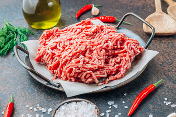 Raw minced beef meat on a tray over black background.