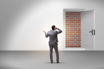 Businessman facing no exit with brick door