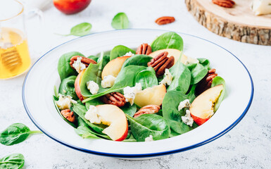 Healthy summer salad with spinach, peach, pecan nuts, blue cheese on white background