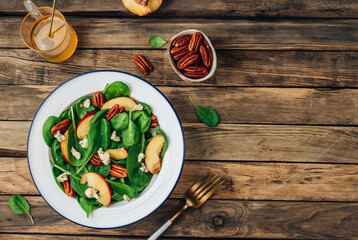 Healthy summer salad with spinach, peach, pecan nuts, blue cheese on wooden table