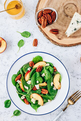Healthy summer salad with spinach, peach, pecan nuts, blue cheese on white background