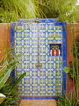 Outdoor tile shower with lush tropical plants at spa.