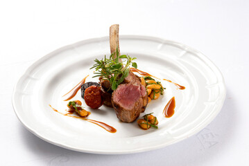 Roast rack of lamb or rack of beef accompanied by beans, served on a white plate on a white...