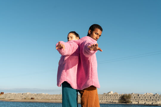 Friends sharing colorful jacket while dancing 