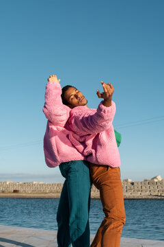 Friends sharing colorful jacket while dancing 