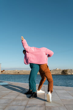 Friends sharing colorful jacket while dancing 