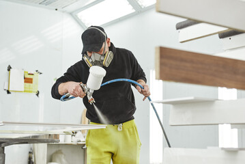 Painters with professional touch. Close up of man in respirator mask painting wooden planks at...