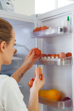 Woman taking fresh eggs from fridge