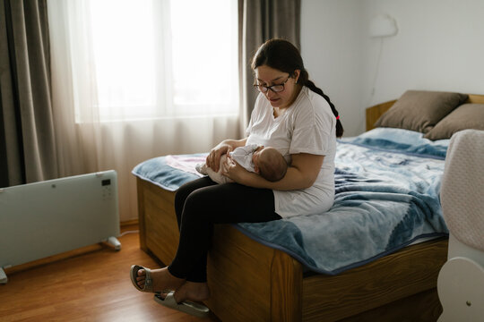Mother holding baby. Lifestyle portrait in the bedroom