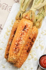 Grilled Sweet Corn with Butter and Shredded Mozarella. Served on White Plate