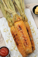 Grilled Sweet Corn with Butter and Shredded Mozarella. Served on White Plate