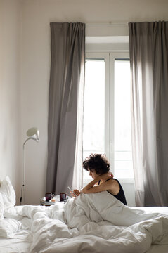 Young woman uses a smartphone in bed. Early morning. 