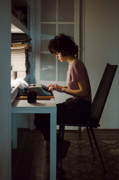 Curly young woman using a typewriter. 