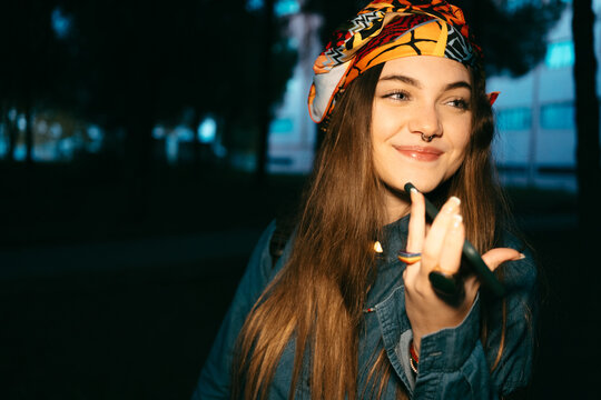 Joyful teen girl with cuban style using phone at night