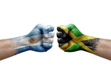 Two hands punch to each others on white background. Country flags painted fists, conflict crisis concept between argentina and jamaica