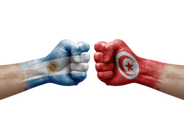 Two hands punch to each others on white background. Country flags painted fists, conflict crisis concept between argentina and tunisia