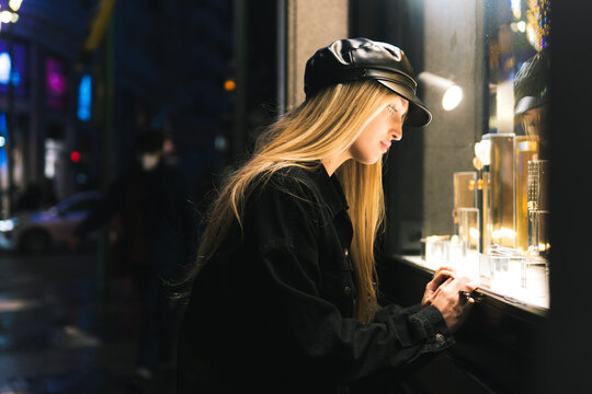 Young female examining jewelry in shop window