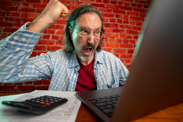 Funny portrait of angry crazy man with laptop tax prep to balance budget getting debt deficit...