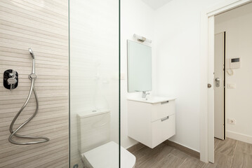 Bathroom with glass-enclosed shower, white sink cabinet and frameless built-in mirror in vacation rental apartment
