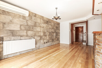 Room with slate tile wall, radiator and air conditioner with oak flooring