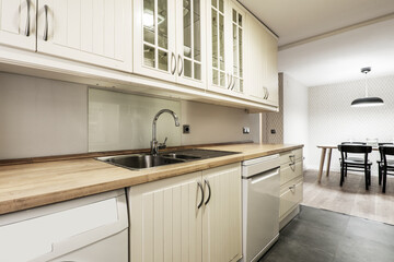 White kitchen cabinets with wooden countertop and dining table in the background