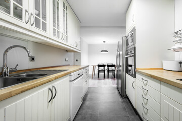 kitchen with wooden furniture and gray appliances and dining table with black chairs in the background