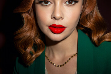 Beautiful woman with red lips and dressed in green looks at the camera.