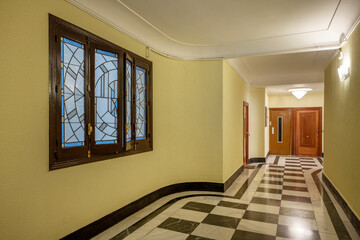 Entrance hall of an old residential apartment building checkered marble floors, elevator and leaded glass window