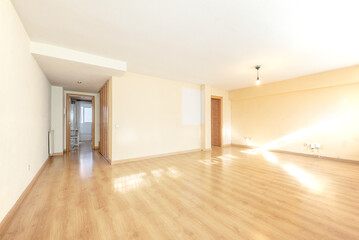 Fototapeta na wymiar Large empty living room with oak colored wooden floorboards and cream painted walls