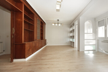 Living room with custom-made wooden bookcase made of mahogany wood, light wooden floors and...