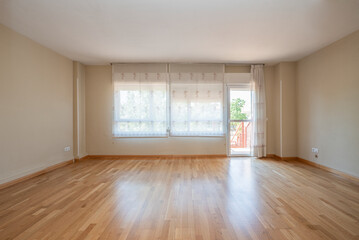 Living room of an empty room with light wood floors and stairs to the patio in a single-family residential home