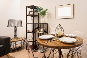 Living room with eclectic and somewhat chaotic decoration with round wooden table and food service set