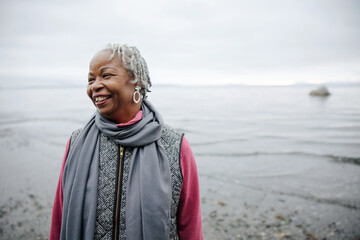Laughing older woman outside at the beach in fall.