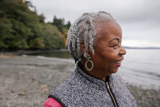 Laughing older woman outside at the beach in fall.