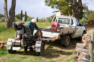 Senior man using a log splitter machine