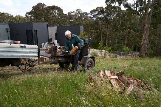 Logs being split for firewood by senior man