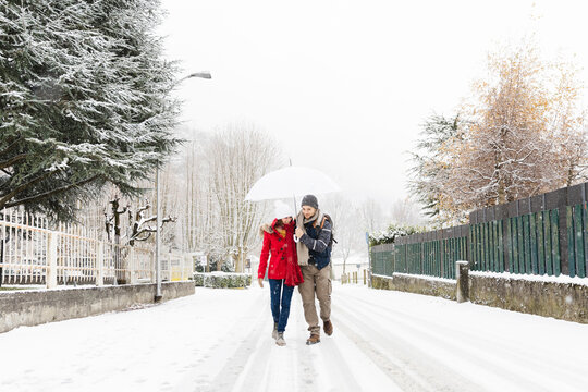 Walking under the snow with umbrella