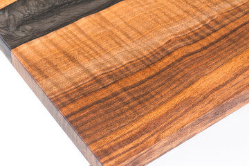 Close up of a Curly Bastogne Walnut wooden coffee table with black epoxy resin and metal legs. White studio backdrop.
